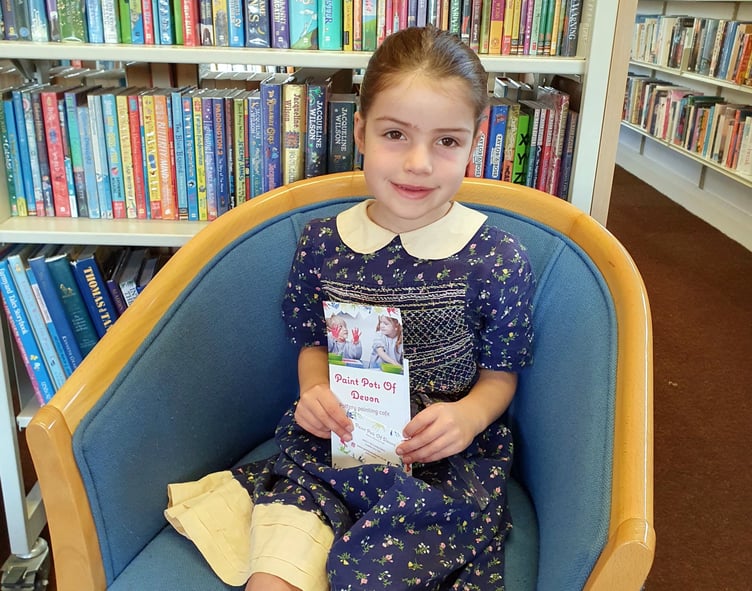 Edie with the £20 Paint Pots of Devon voucher she won in the Summer Reading Challenge.