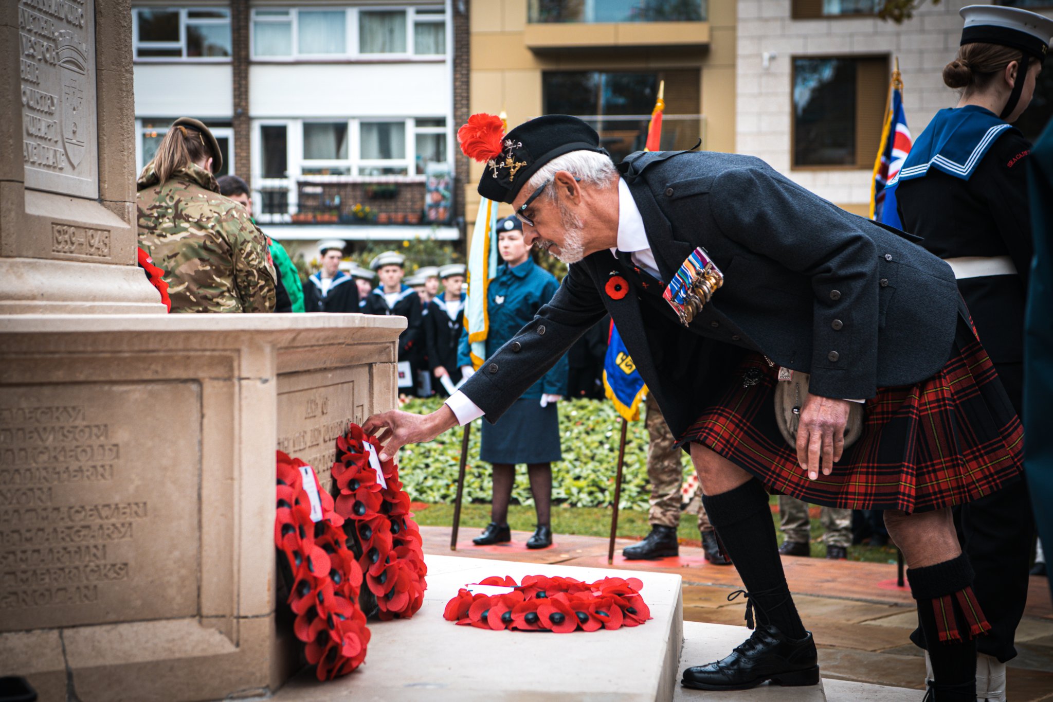 A kilt-clad member of the Farnham Royal British Legion Branch lays a wreath