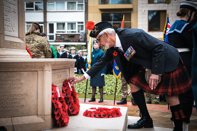 A kilt-clad member of the Farnham Royal British Legion Branch lays a wreath