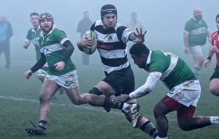 As the mist descends, Oscar Henderson fends off the defender