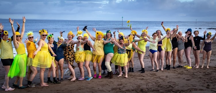 Minehead Mermaids adorned with sunflowers cheering before their dip.