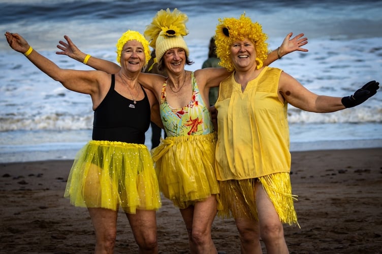 A trio of Minehead Mermaids smile before entering the water.