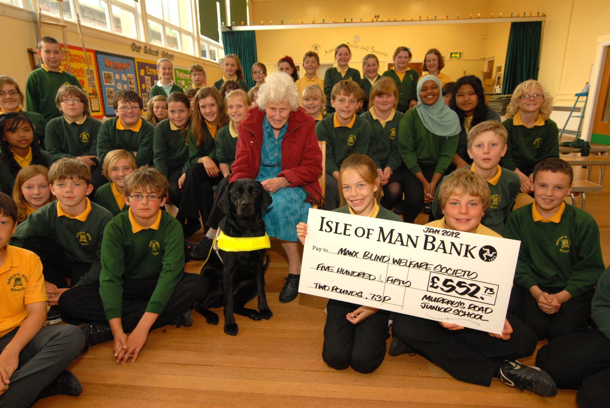 June Sanderson receiving a cheque from children at Murrays Road School on behalf of the Manx Blind Welfare charity after pupils raised over £550 for audiobooks. Inset, an old picture of June