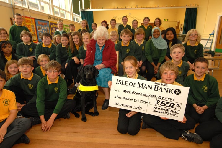 June Sanderson receiving a cheque from children at Murrays Road School on behalf of the Manx Blind Welfare charity after pupils raised over £550 for audiobooks. Inset, an old picture of June