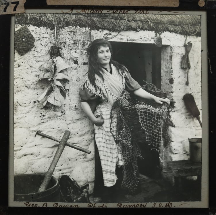 Manx fisher girl Miss Crennell, pictured outside her thatched cottage in an image from late 19th or early 20th century