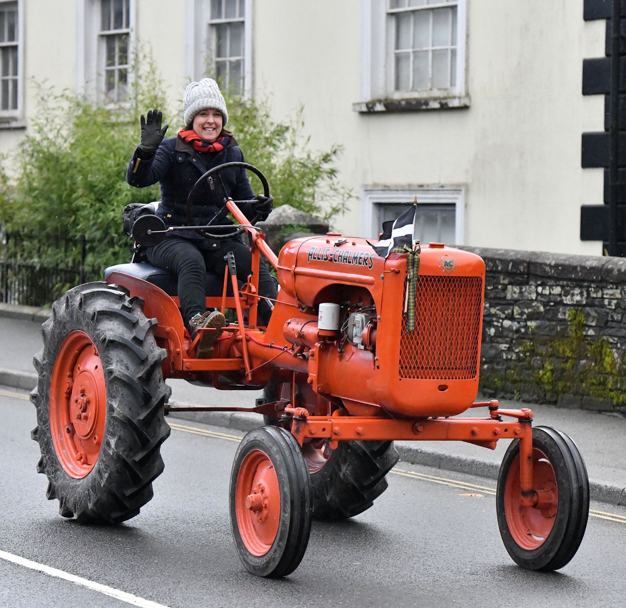 A wave from Elaine Reynolds as she makes her way through Camelford on her Allis Chalmers B Tractor