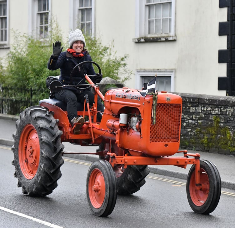 A wave from Elaine Reynolds as she makes her way through Camelford on her Allis Chalmers B Tractor