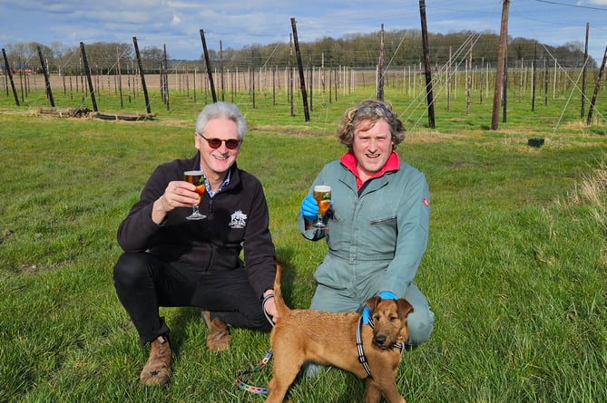 Hogs Back Brewery managing director Rupert Thompson (left) and hop garden manager Matthew King toast the brewery’s shortlisting in the SIBA Sustainable Business Award, accompanied by brewery dog Basil