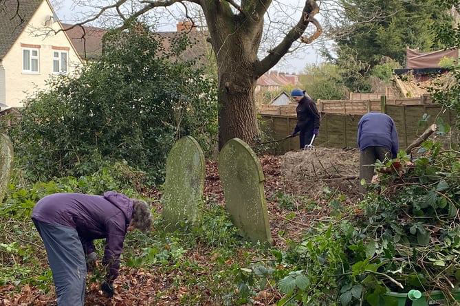 Members of the new Wrecclesham Conservation Group collect fallen branches into log piles at St Peter's churchyard