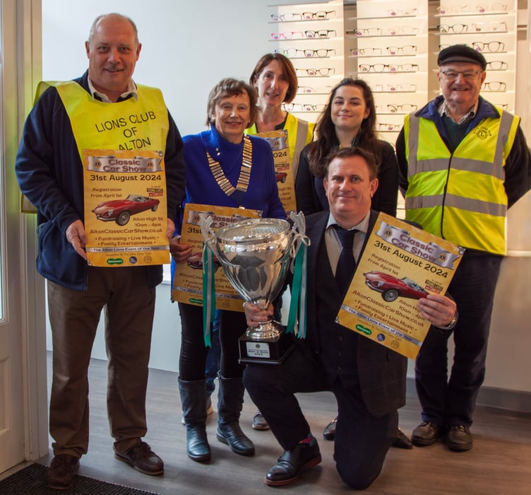 The 21st Alton Classic Car Show is launched with the trophy going on display at major sponsor Specsavers. From left: Alton Lions John Mill, Moira Baker (president), Lisa March and Mike Baker, with Specsavers optical assistant Chloe Knight and Dean-Paul Phillips (kneeling), chief executive of The Little Grey Cells, April 2024.