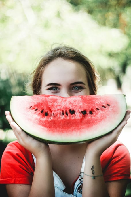 A woman smiling with a smile holding a smily watermelon