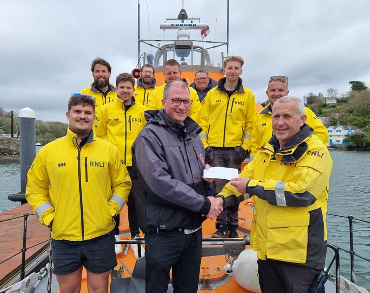 Henry Orchard presents a cheque to coxswain Jonathan Pritchard. Picture: Fowey RNLI