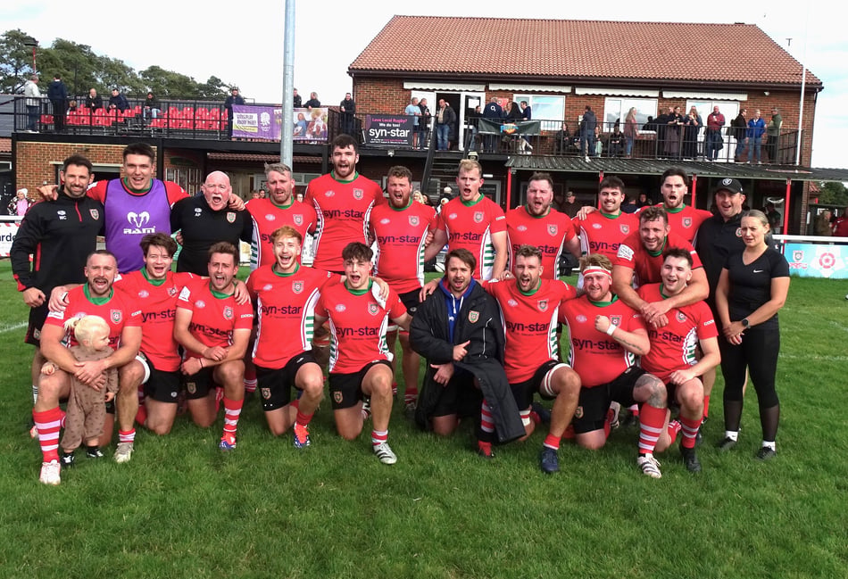 <p>A happy Petersfield squad celebrate victory with their coaches and support staff (Photo: Chris Todd)</p>
