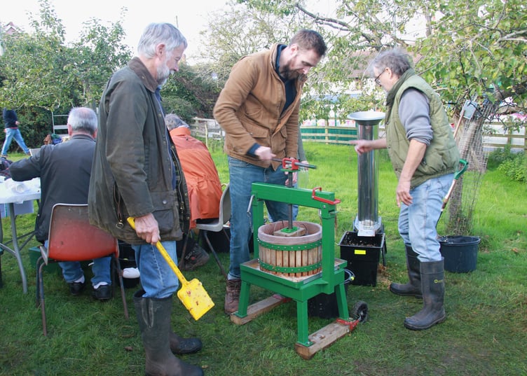 Stuart Heesom and Sam Parker-Gill pressing apples in Carhampton Community Orchard. PHOTO: George Ody.