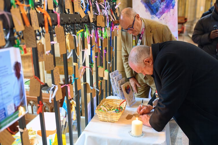 Bishop David writes a message at Truro Cathedral's LOUD Fence