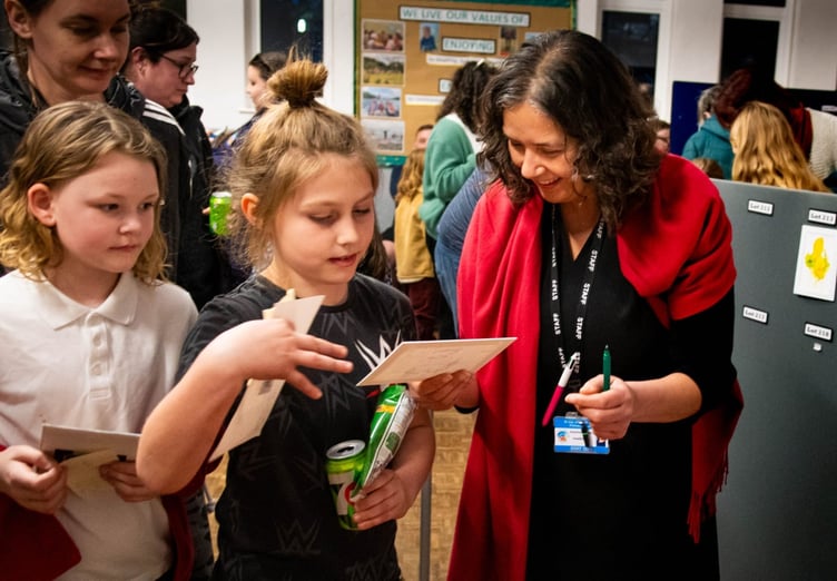 Headteacher Susannah Storey hands handing Sonny the artwork piece he has successfully bid for at the St Day & Carharrack Community School anonymous art auction