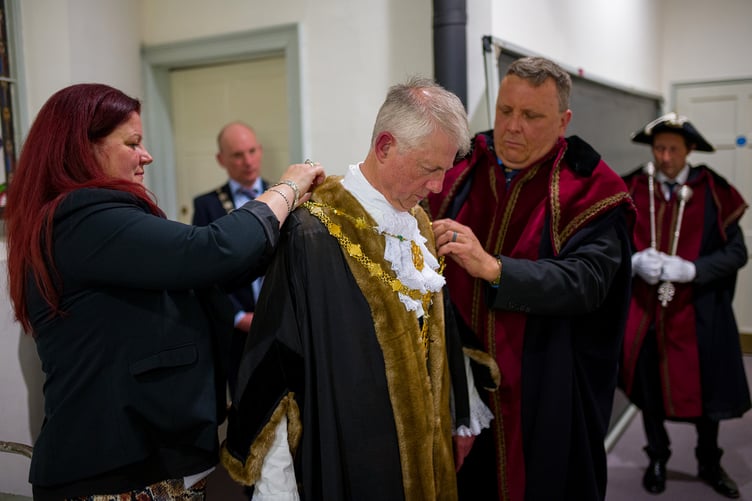 Cllr Chris Wells is helped to dress in the formal mayoral robes