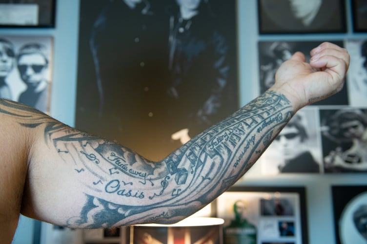 Oasis superfan John Smallbones Oasis tattoos. See SWNS story SWOCoasis; Meet the Oasis superfan who has spent THOUSANDS on band memoribillia including life size cut outs of the Gallagher brothers - and his fiancee isn't even a fan. John Smallbones, 45, fell in love with the band back in 1992 and was devastated when the brothers went their separate ways. Over the past decade, window surveyor John has spent thousands of pounds on Oasis merchandise including vinyls, clothing and life size cutouts of both Gallagher brothers. He's even got Oasis tattoos and has named his business 'Wall of Glass' after the popular 2017 Liam Gallagher hit with a van plastered in stickers dedicated to the boys. His home is covered top to bottom with Oasis memorabilia, much to the amusement of his extremely patient fiancee Elaine, 46, who isn't even a fan of the band.