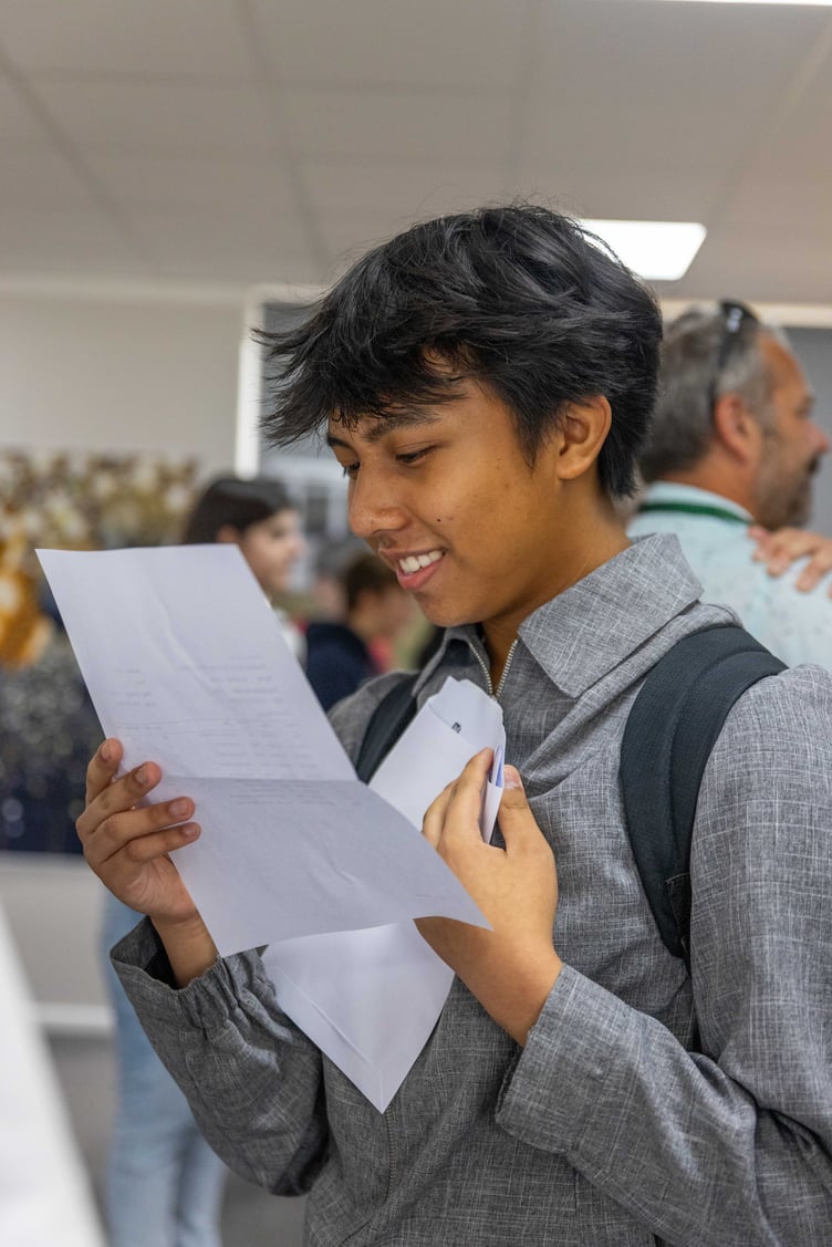 A student smiles as they open the envelope containing their GCSE exam results (Picture: CELT)