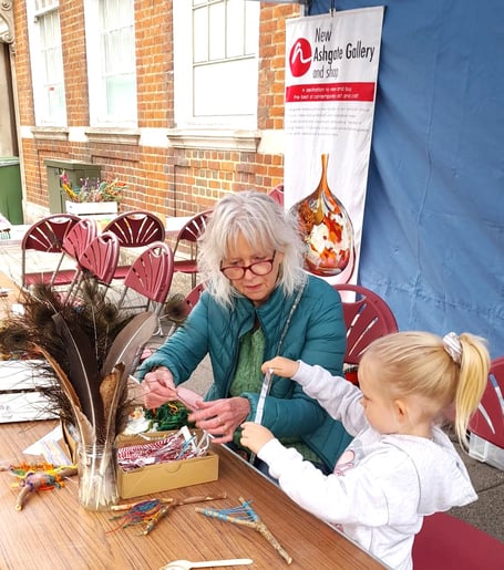 Former Surrey Artist of the Year Jane Browne teaches branch weaving to a young student, Farnham Food Festival, September 28th 2025.