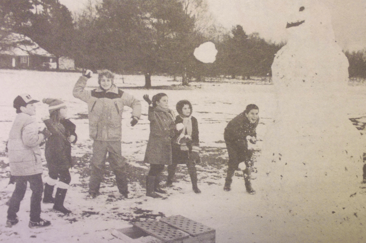 Snowballing children take aim at a ten feet high snowman on Butser Hill, January 5th 1985.