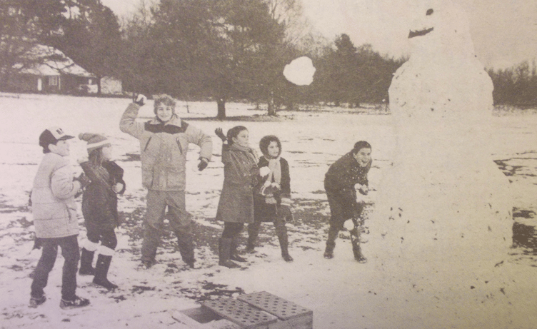 Snowballing children take aim at a ten feet high snowman on Butser Hill, January 5th 1985.