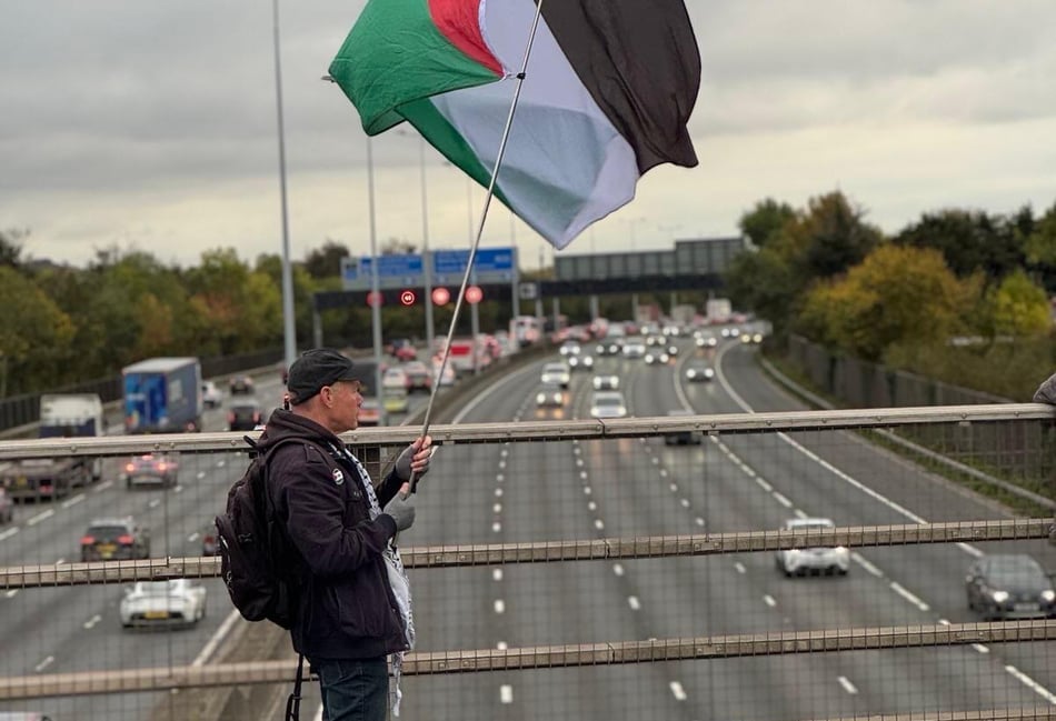 <p>A demonstrator from the West Surrey Palestine Solidarity Campaign holds a flag during a peaceful protest on New Wickham Lane, Egham, on October 15.</p>
