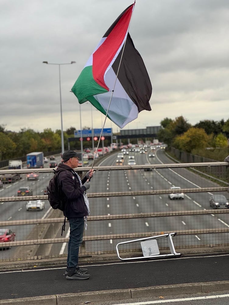A demonstrator from the West Surrey Palestine Solidarity Campaign holds a flag during a peaceful protest on New Wickham Lane, Egham, on October 15.