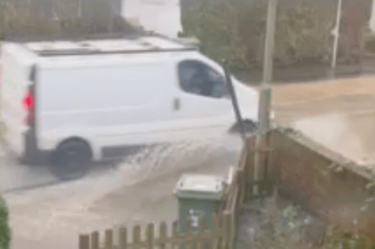 A van drives through a flooded street in Tongham.