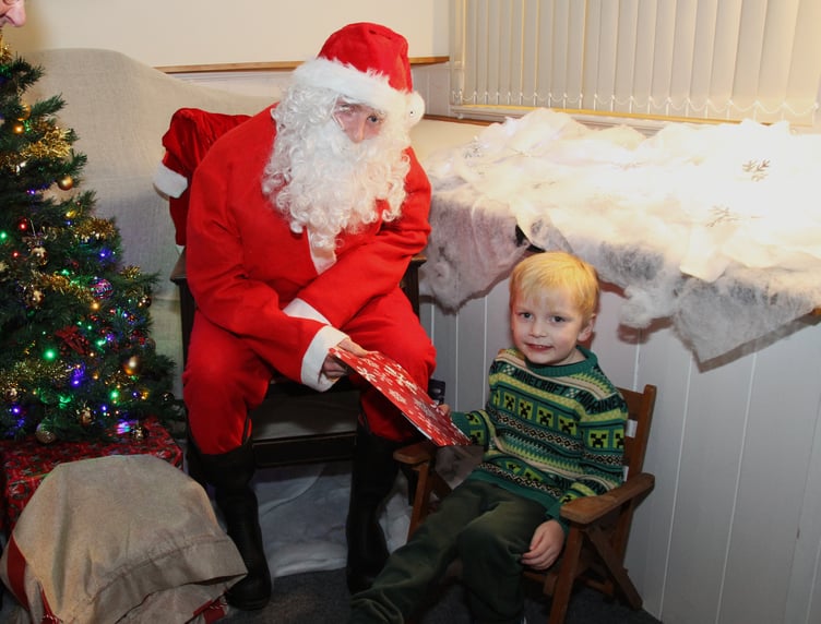 Thiago Huish receives an early Christmas present from Santa during the switch on of Porlock's festive lights. PHOTO: George Ody.