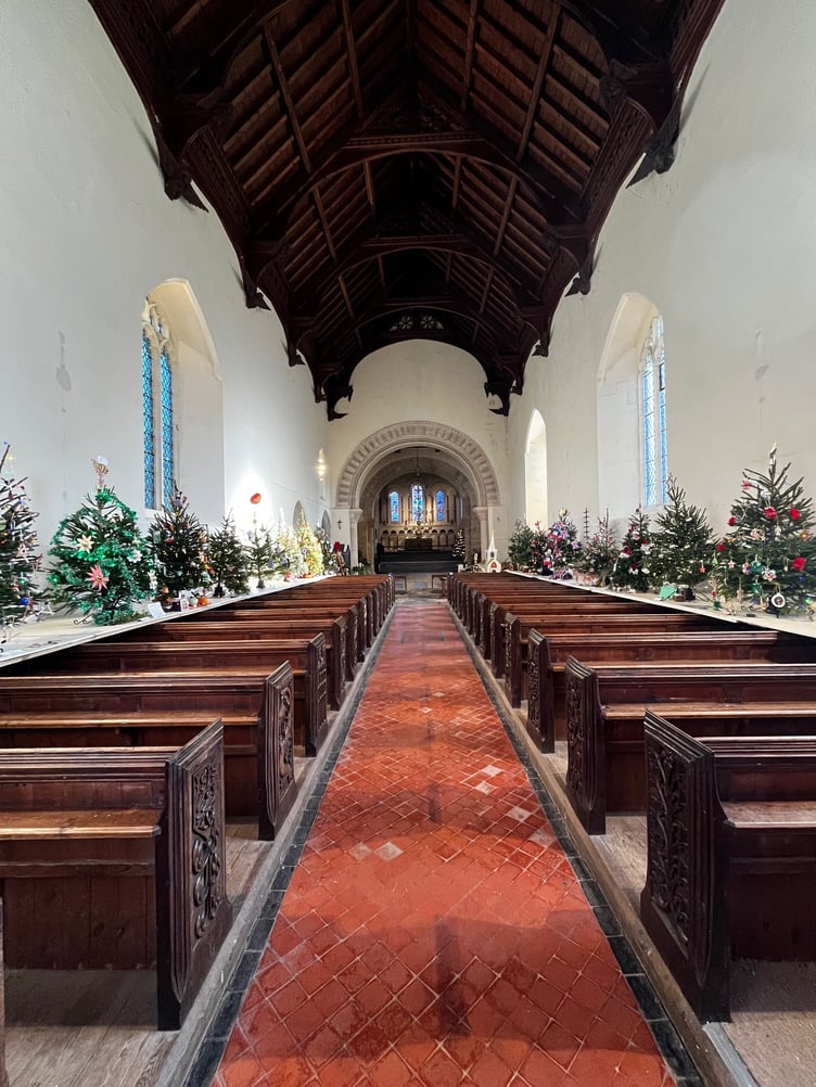 A view along the aisle of St Andrew's Church, Stogursey, during its Christmas tree festival.