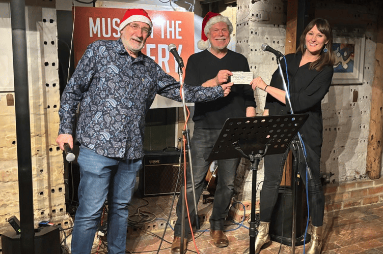 Peter Crutchfield and Jim Cozens present a cheque for £2,150 to Kathryn McManus, chief executive of Creative Response, Music At The Pottery, Farnham Pottery, December 19th 2025.