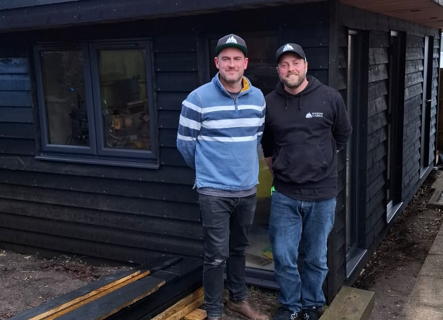 <p>Tom Chapman and Laurence Nicholls outside a cabin they are building in Tom's garden.</p>