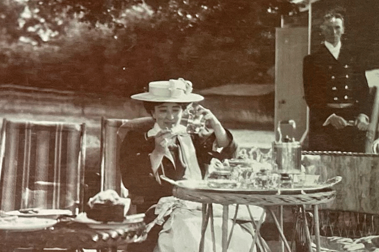 A lady enjoys a picnic on the lawn of Frensham Hill.