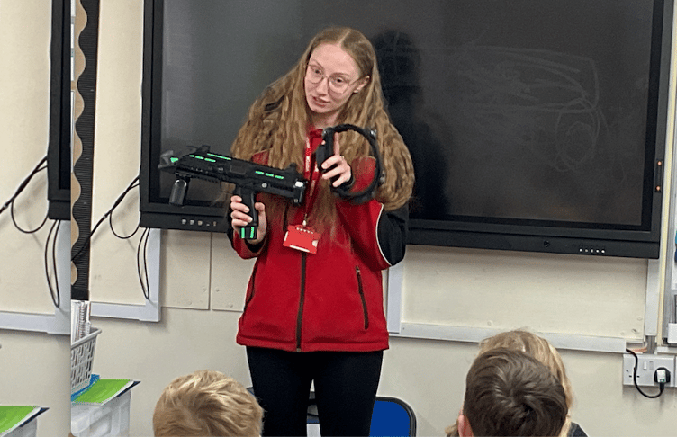 Butlin's sports activities shift manager Demi Millin shows off a laser tag weapon to pupils of Minehead Middle School.