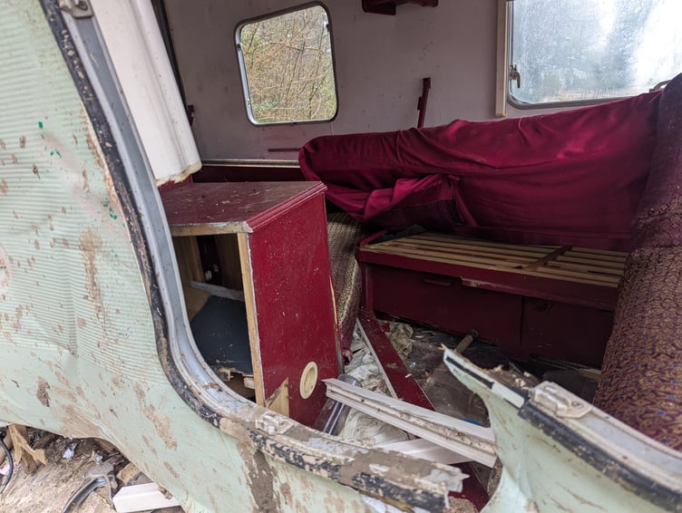 Items can be seen to have spilled out from a caravan that has been dumped.
