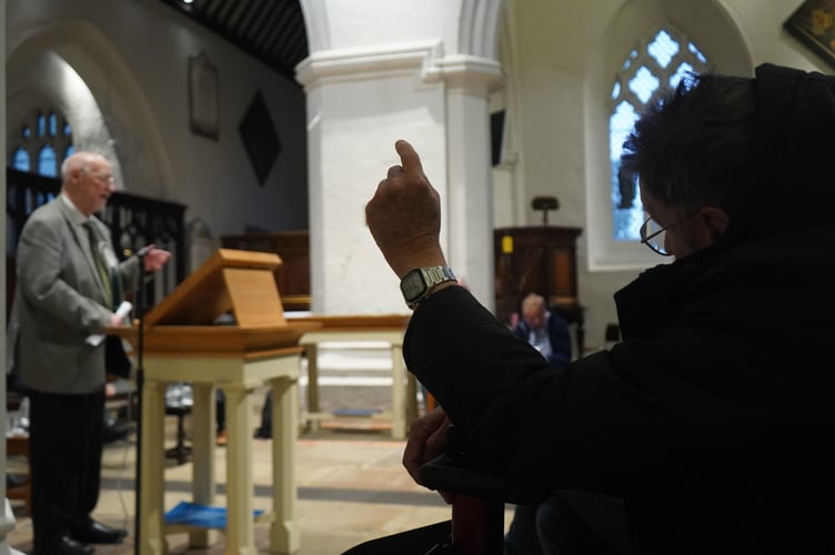 Audience member raising their hand to ask questions at the Hustings