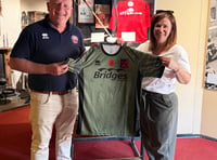 <p>Aldershot Town commercial manager Mark Butler shows off the signed Remembrance game shirt at Aldershot Military Museum (Photo: Ian Morsman). </p>