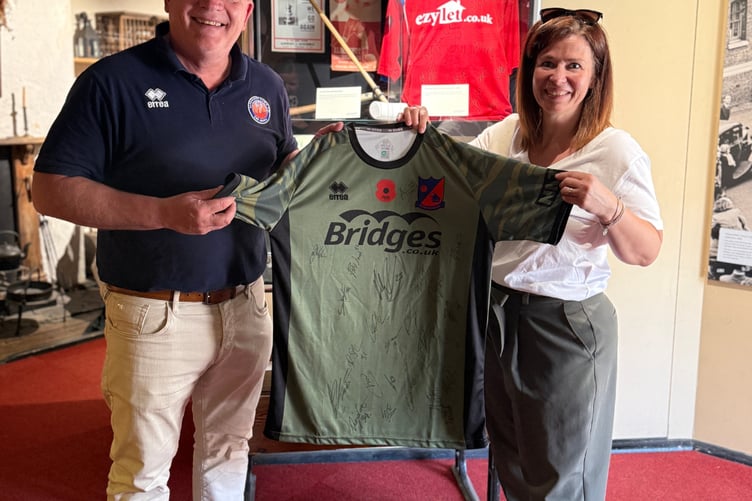 Aldershot Town commercial manager Mark Butler shows off the signed Remembrance game shirt at Aldershot Military Museum, June 25th 2026.