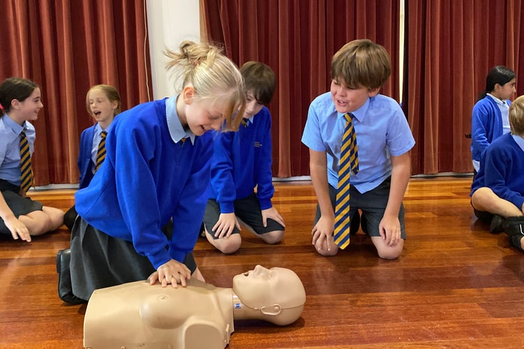 Student giving CPR to a dummy to the music of Stayin' Alive by the Bee Gees