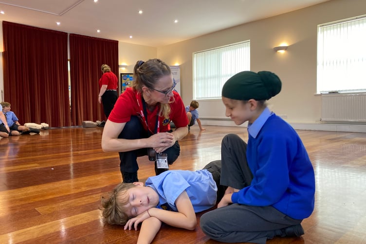 Jo Michaelides is teaching a South Farnham Student the recovery position